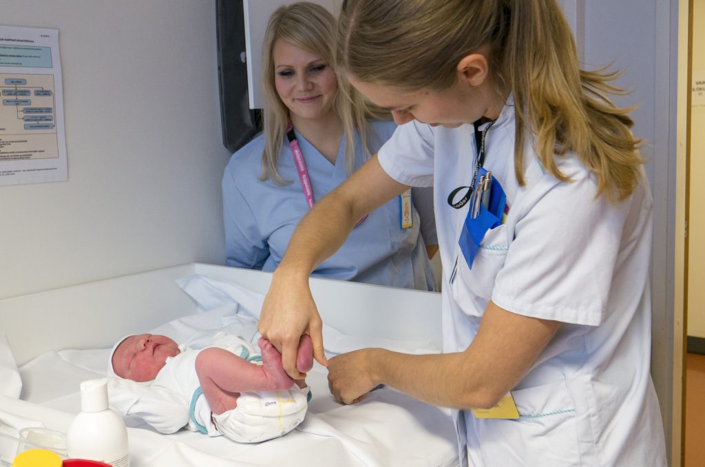 Opiskelija Johanna Tähkäpää tekee vauvalle hoitotoimenpiteitä, opiskelijavastaava Anni Uusitupa seuraa tilannetta.