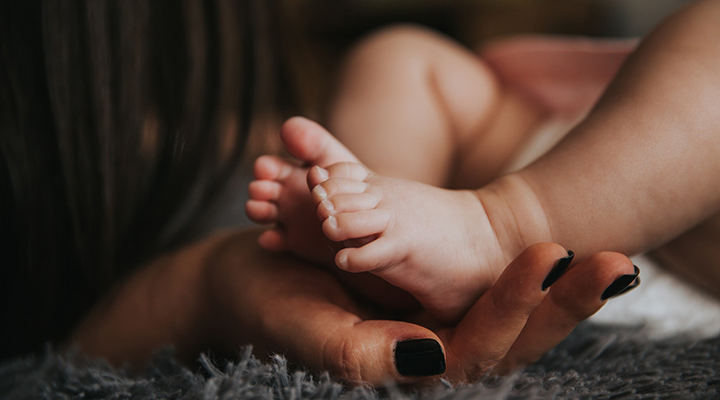 Vauvan jalat naisen kämmenellä