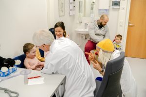 Kuvassa on lääkäri tutkimassa lasta sekä sairaalaklovni mukana tutkimuksessa.