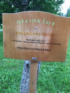 Kyltti Näkymä 2019 -ympäristötaidefestivaalilta. Teoksessa mainitaan Monosen ja Mansikkalan teos.