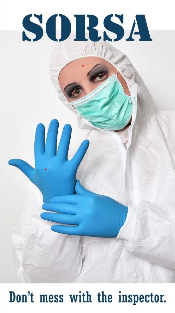 Kuvassa on lääketieteellisiin suojavarusteisiin pukeutunut henkilö. Kuvan alaosassa lukee "Don't mess with the inspector".