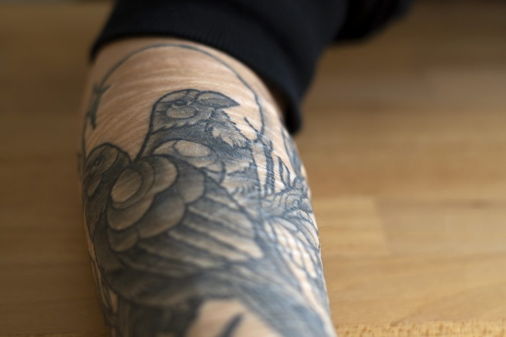 Kuvassa on tatuoitu käsi; tatuoinnissa on kaksi lintua.
