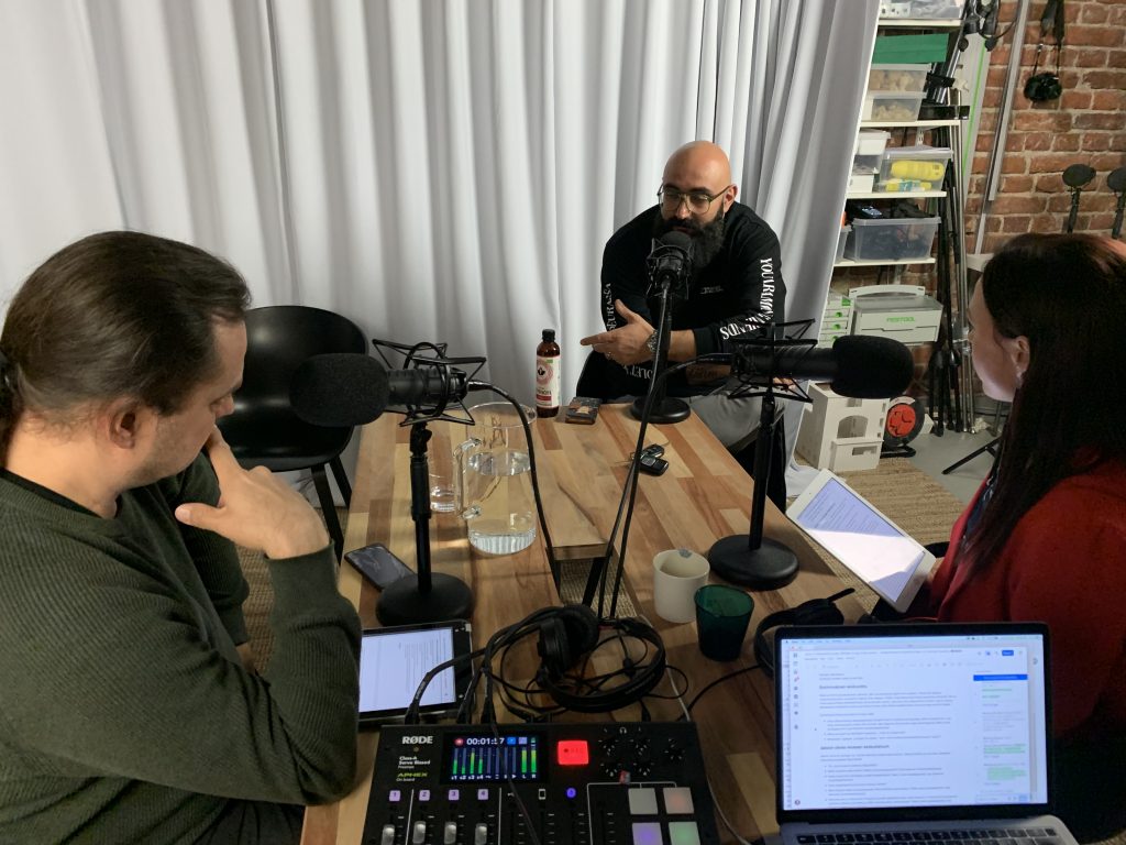 Kuvassa on kolme henkilöä pöydän äärellä tekemässä podcastia.
