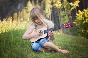 Kuvassa lapsi soittaa ukulelea.