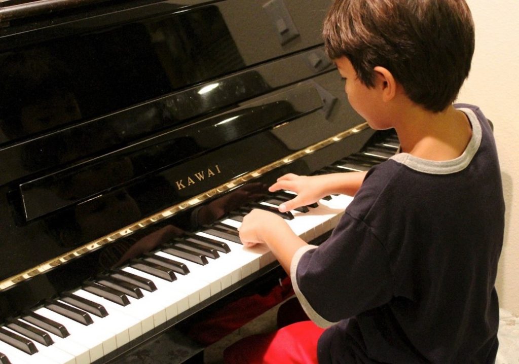 Kuvassa lapsi soittaa pianoa.