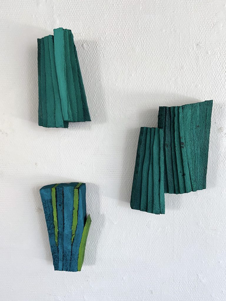 Kuvassa on taiteilija Laura Laurilan veistoryhmä. Teokset ovat sävyiltään sinivihreitä.