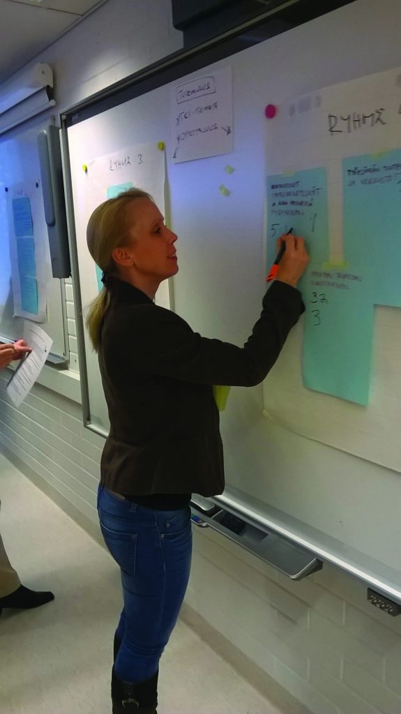 A woman is about to write on a piece of paper on a board.