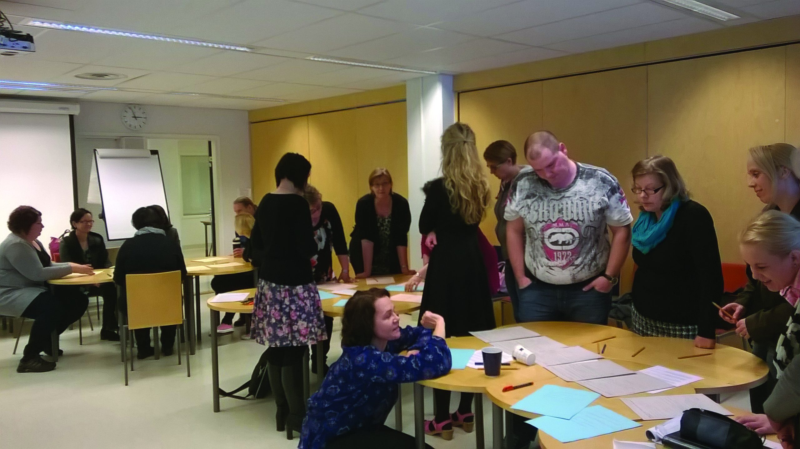 Groups of people gathered around different tables to look at the papers on them.