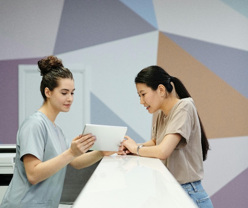 Työasussa oleva hoitaja ja muu terveysalan ammattilainen pohtivat ammattikysymystä.