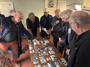 Ikämiehiä tutkimassa pöydällä olevia vanhoja valokuvia