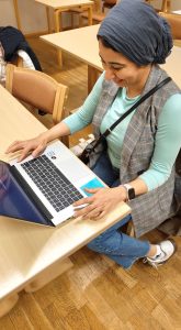 Mona, ulkomaalaistaustainen opiskelija tietokoneellaan työpöydän ääressä,