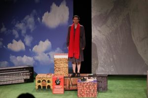 Fiona Bawn-Thompson näyttämöllä edessään laatikoista muodostuvat lavasteet.