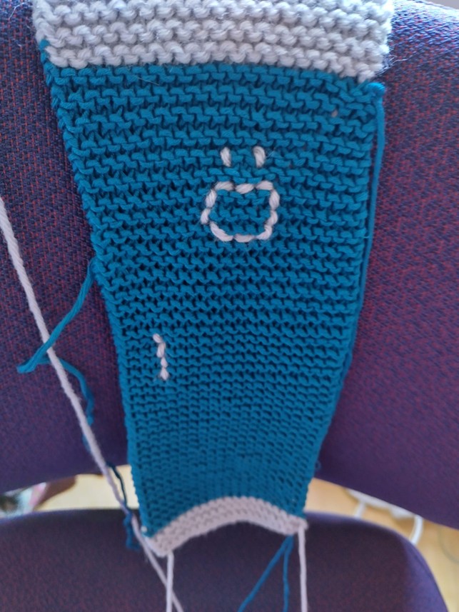 Neulostyö kuvaa ovea, jossa näkyy ikkuna ja kahva.