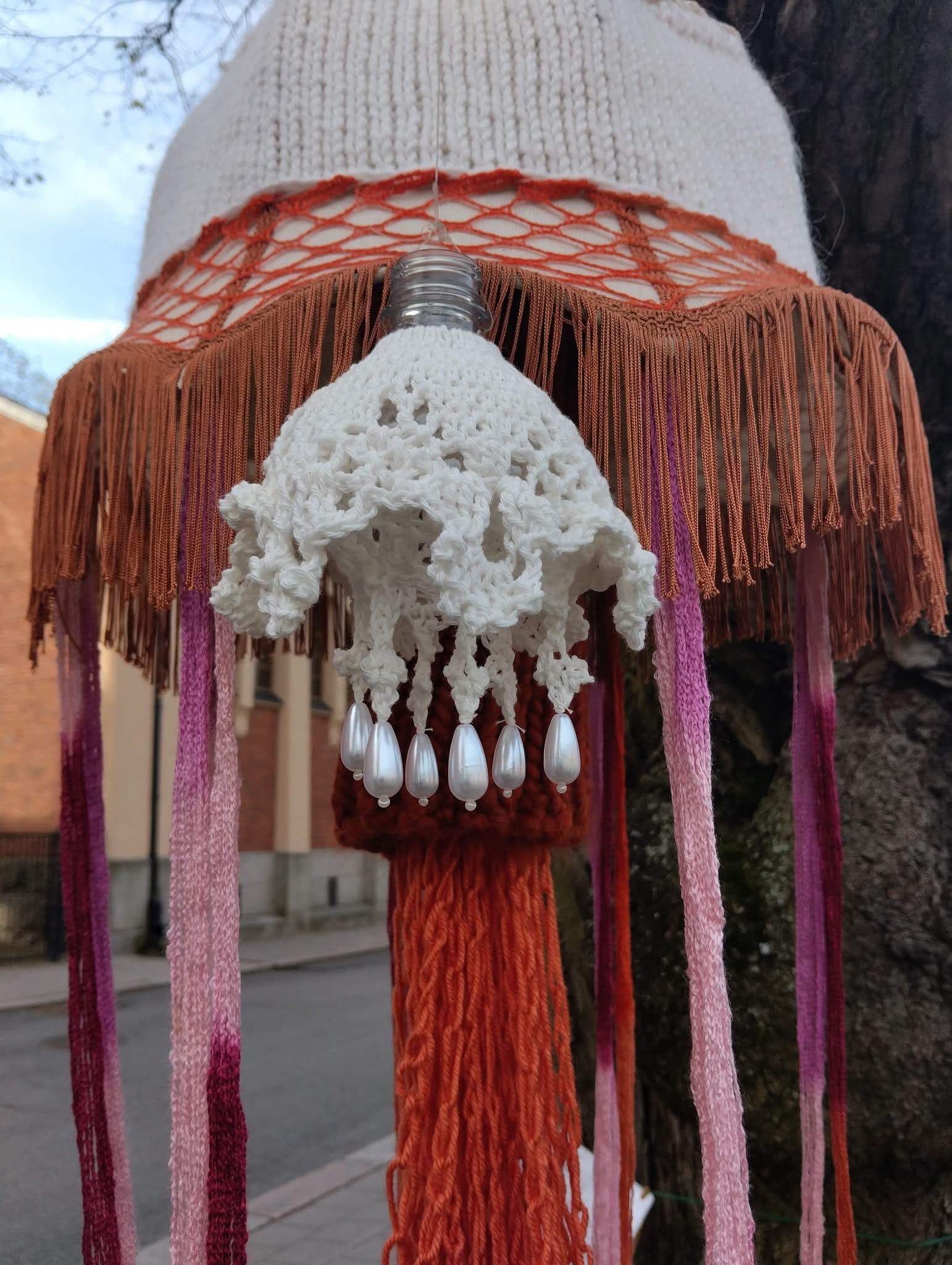 Neuloen ja virkaten tehtyjä "meduusoja" puussa roikkumassa.