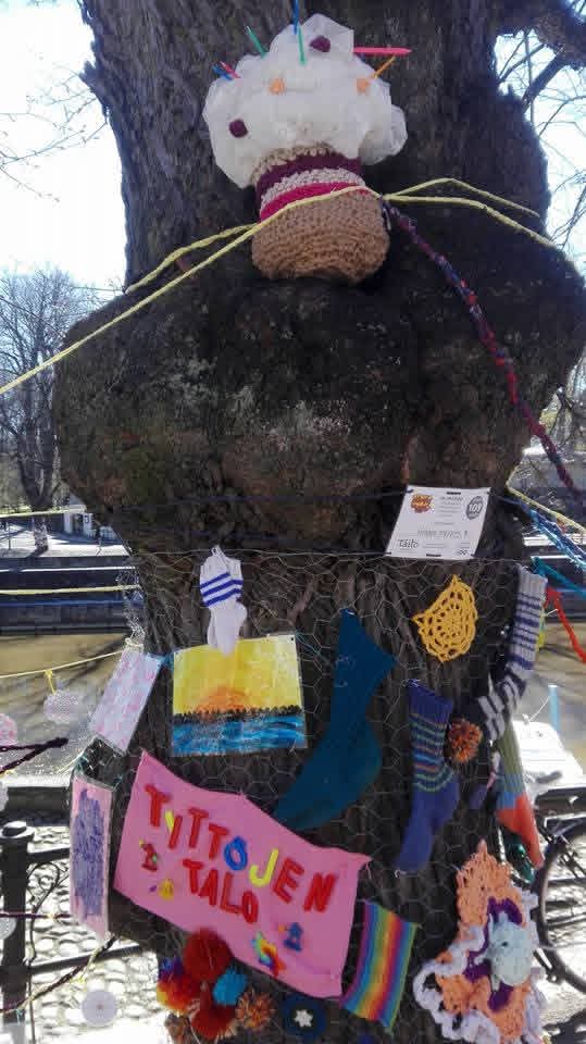 Puu, johon kiinnitetty erilaisia käsitöitä ja tekstikortteja. Yhdessä lukee Tyttöjen talo.