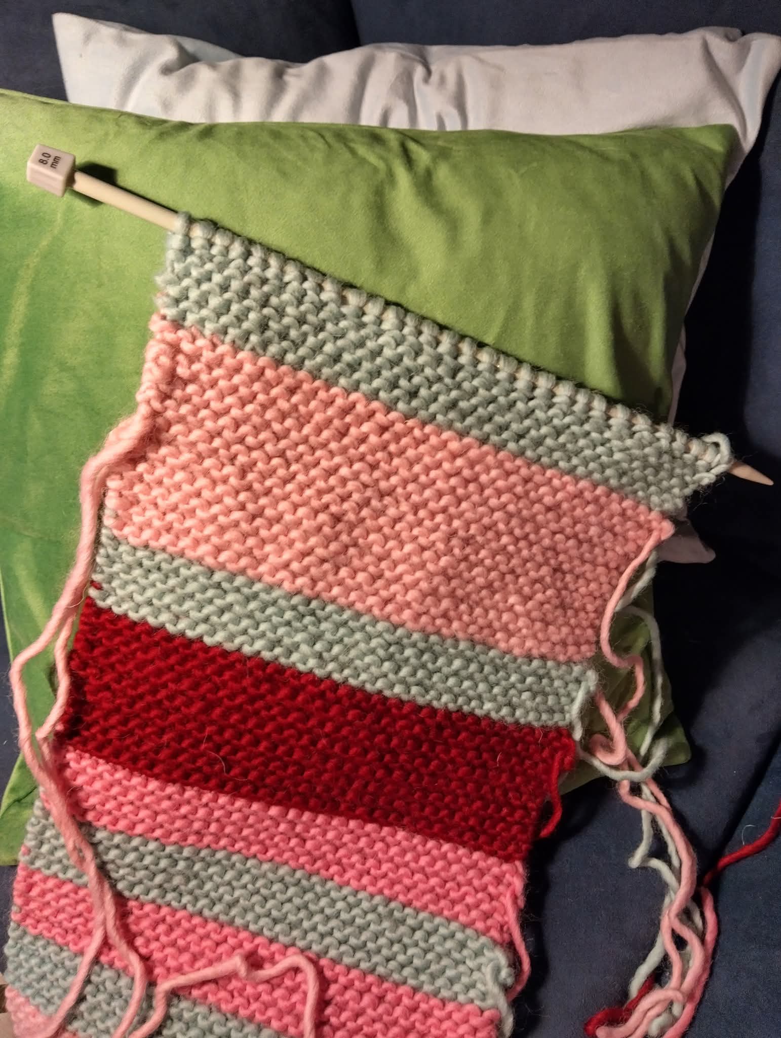 Tyynyjä ja raidallinen neuletyö.