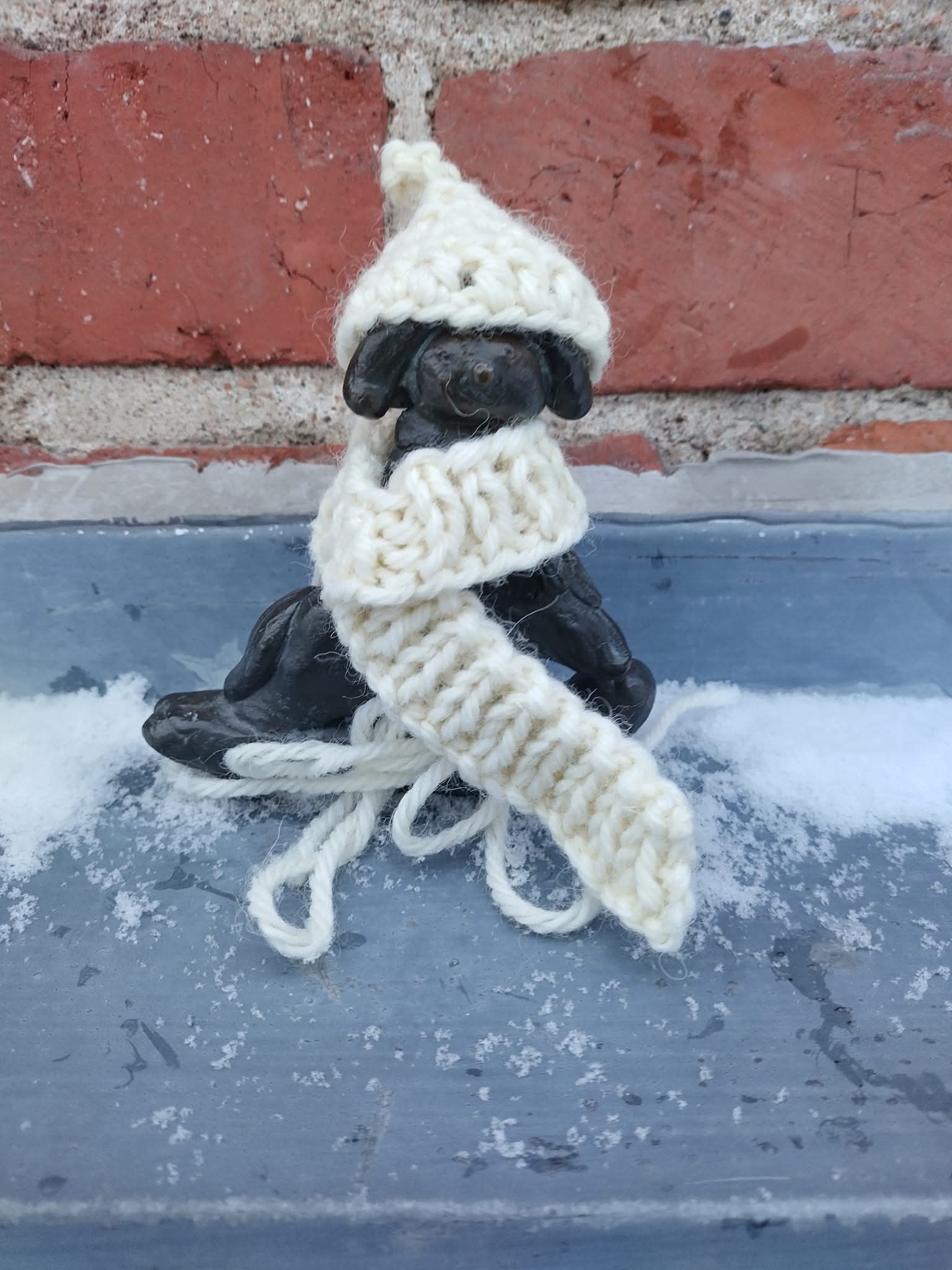 Pieni koirafiguuri on saanut päähänsä pipon ja kaulaansa huivin.