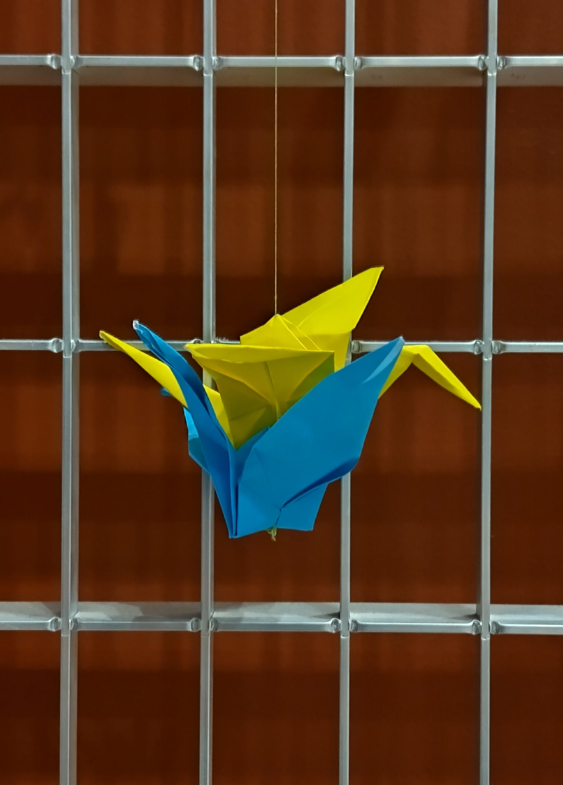 Paperista taiteltu origamikurki seinälle kiinnitettynä.