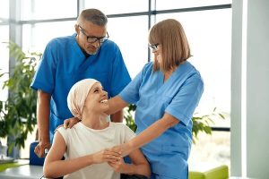 kaksi hoitajaa tukee istuvaa nuorta potilasta