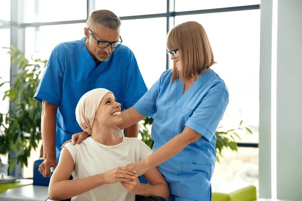 kaksi hoitajaa tukee istuvaa nuorta potilasta