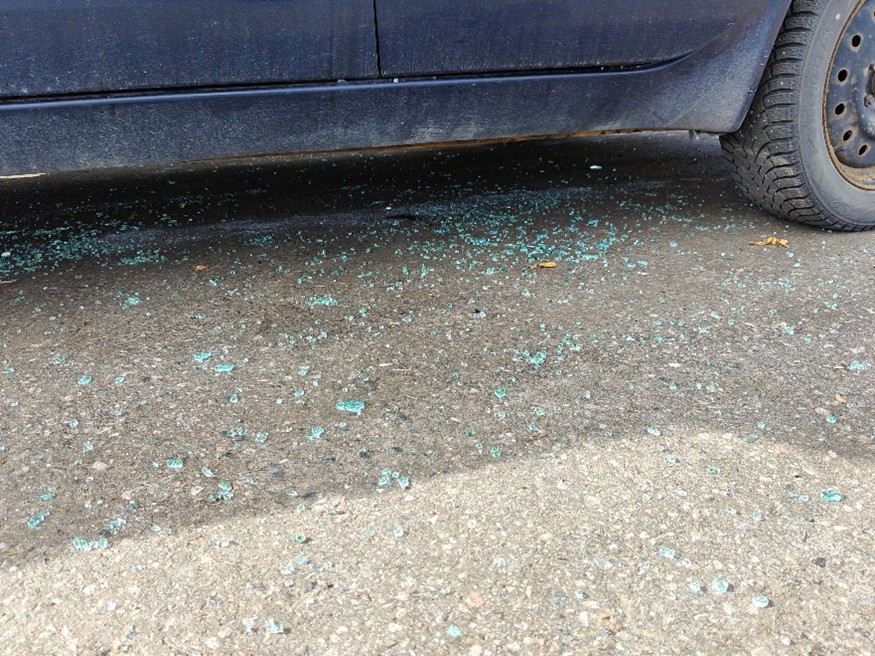 Pihalla on auto ja maassa sen edessä näkyy lasinsiruja, 