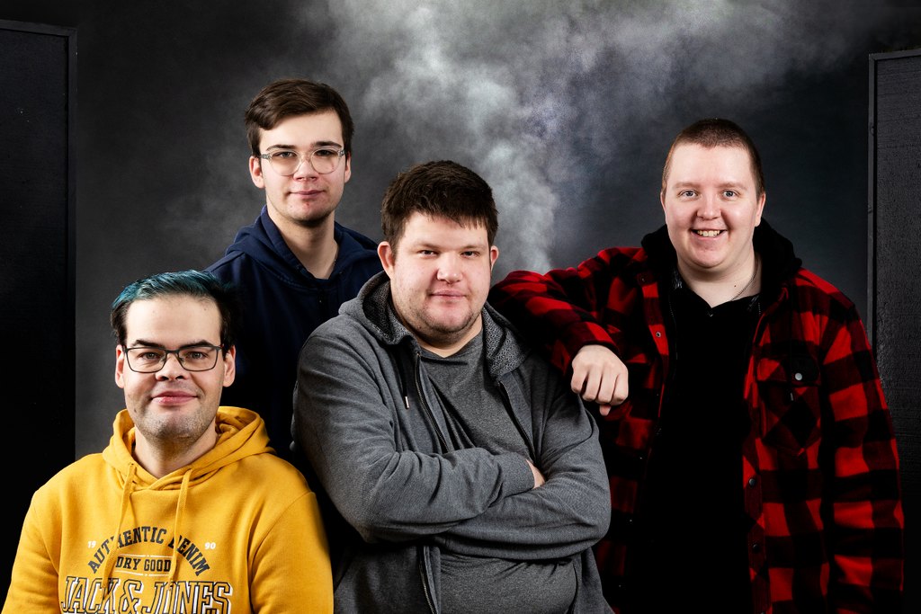 Kuvassa on neljä miesoletettua studiossa. Taustalla näkyy savua.