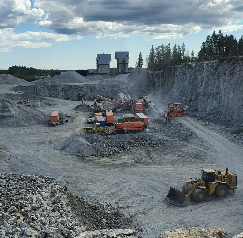 Kuvassa esitetään murskauslaitos Tuusulassa. Kuvassa näkyy murskauslaitos sekä työkoneita, laitoksen ympärillä näkyy kallion seinämää.